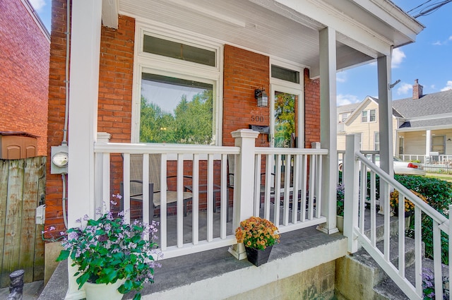 entrance to property with brick siding and a porch