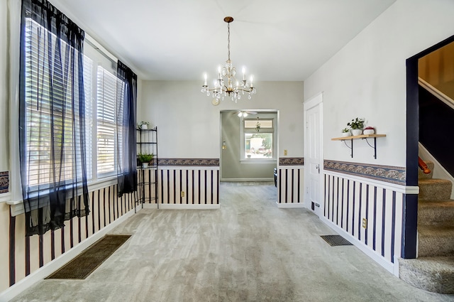 hallway featuring plenty of natural light, wainscoting, carpet flooring, and stairs