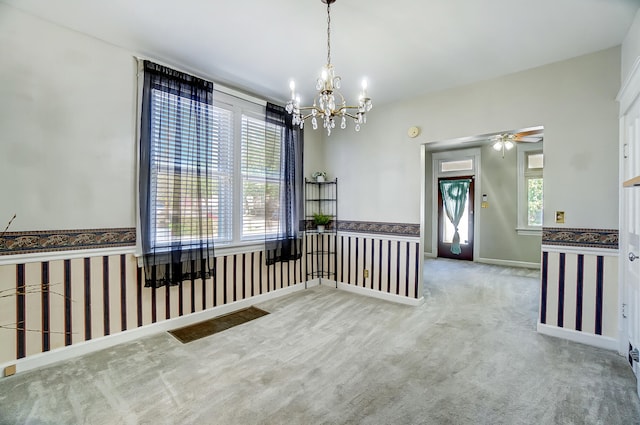 unfurnished room featuring ceiling fan with notable chandelier, baseboards, and carpet floors