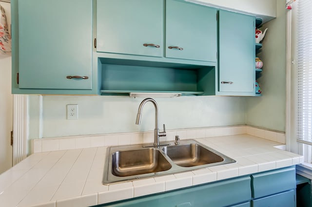 kitchen featuring open shelves, blue cabinets, and a sink