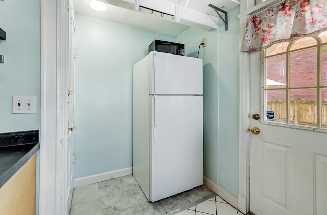 kitchen featuring baseboards, freestanding refrigerator, and black microwave