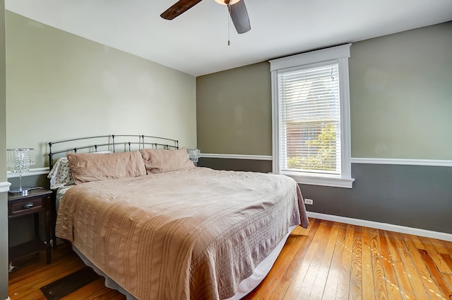 bedroom with a ceiling fan, baseboards, and hardwood / wood-style flooring