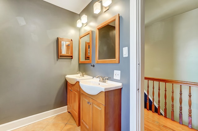 bathroom with tile patterned floors, double vanity, baseboards, and a sink