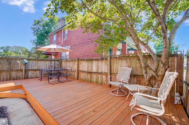 wooden terrace with outdoor dining area and fence