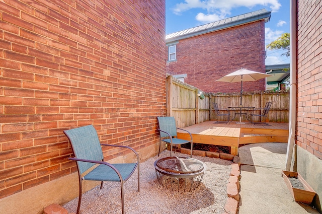 view of patio with an outdoor fire pit, fence, and a wooden deck