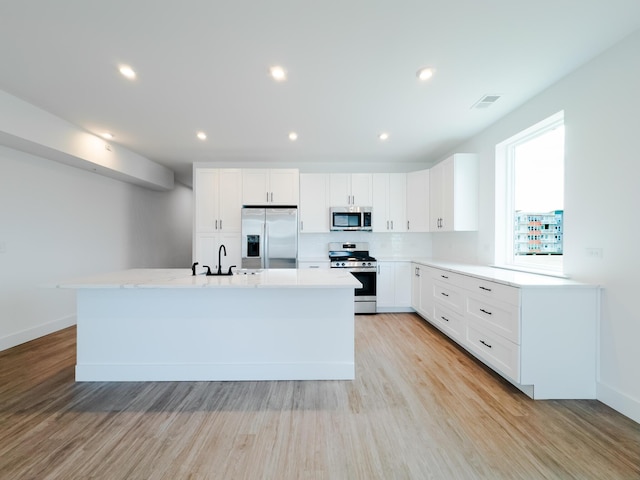 kitchen with light wood-style flooring, appliances with stainless steel finishes, and light countertops