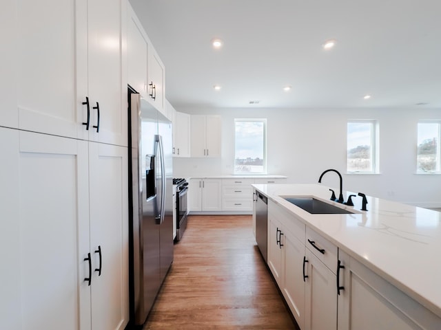 kitchen with a wealth of natural light, white cabinets, stainless steel appliances, and a sink