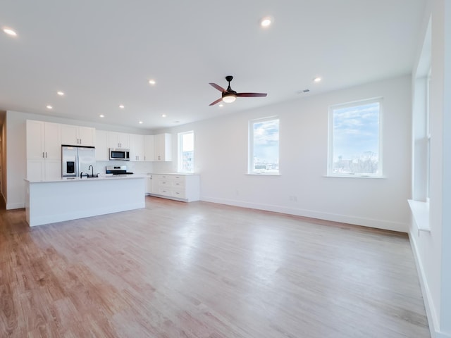 unfurnished living room featuring a ceiling fan, recessed lighting, baseboards, and light wood finished floors