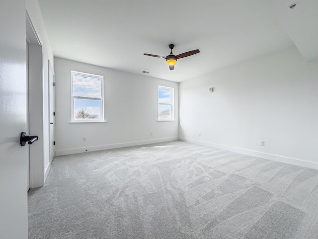 empty room featuring visible vents, light colored carpet, and baseboards