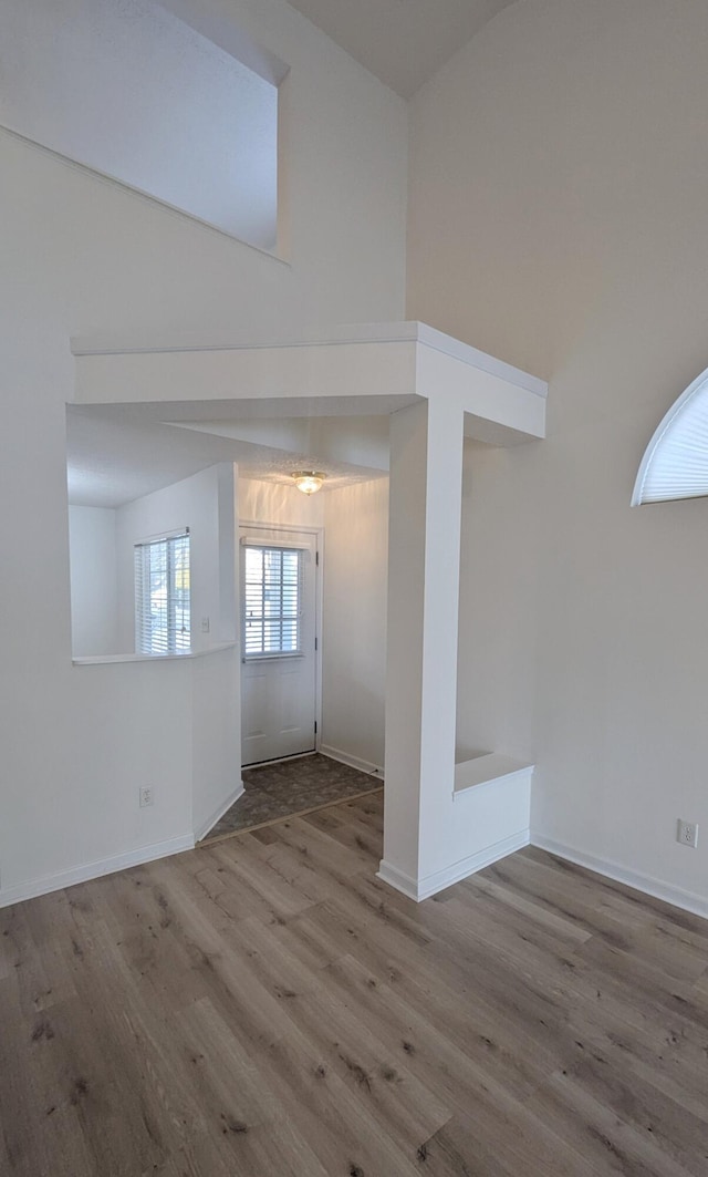 interior space featuring a high ceiling, baseboards, and wood finished floors