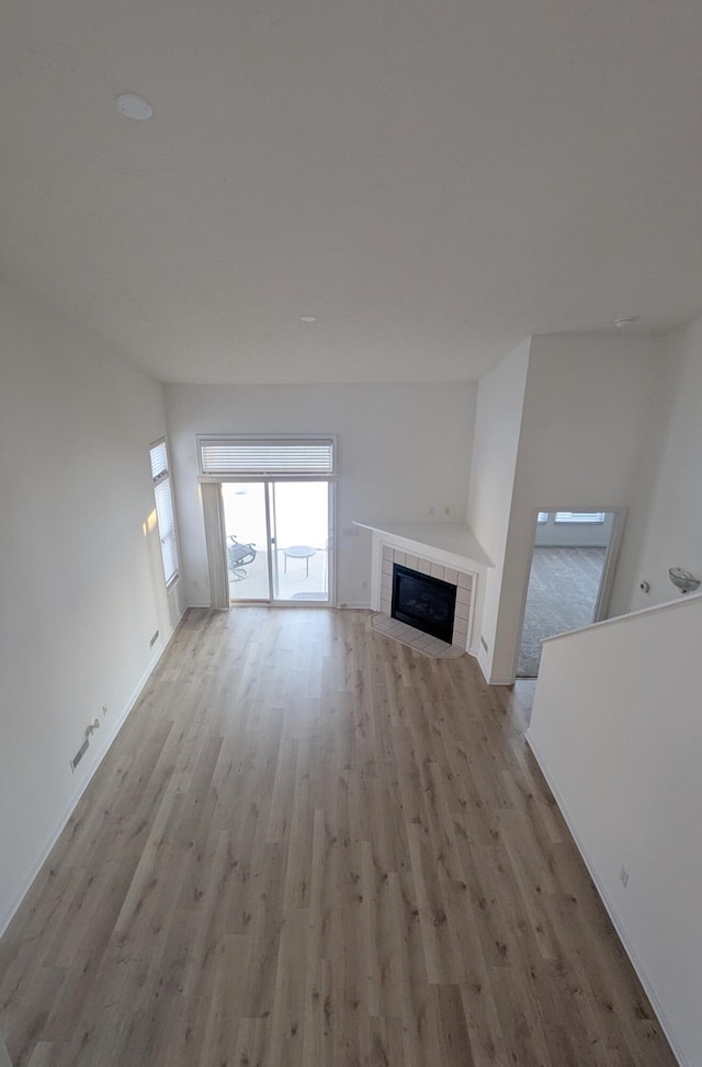 unfurnished living room with a fireplace and light wood-type flooring