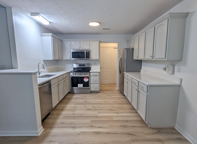 kitchen with visible vents, light wood-style flooring, a sink, a textured ceiling, and stainless steel appliances