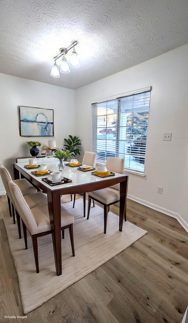 dining room featuring wood finished floors, baseboards, and a textured ceiling