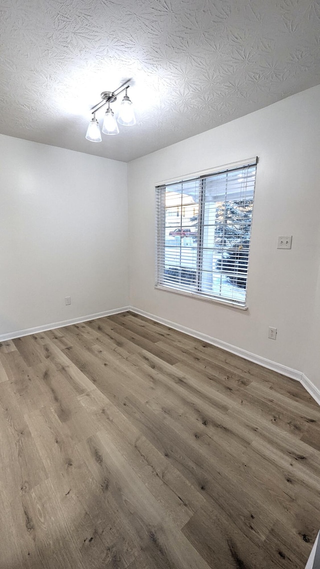 unfurnished room featuring baseboards, a textured ceiling, and wood finished floors