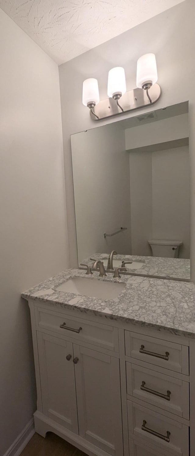 bathroom with vanity, baseboards, visible vents, and a textured ceiling