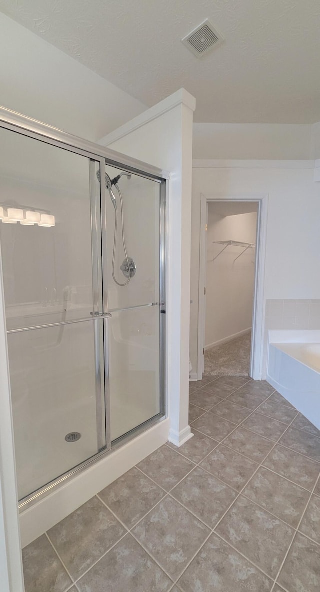 bathroom featuring tile patterned floors, visible vents, a stall shower, and a spacious closet