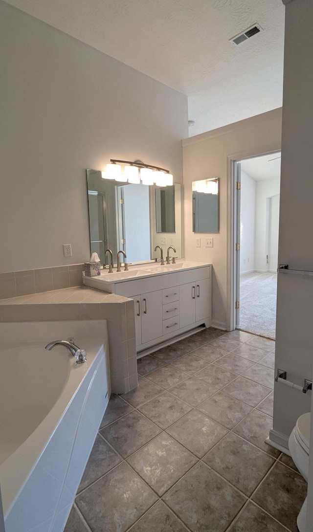 full bath with tile patterned flooring, visible vents, vanity, and a garden tub