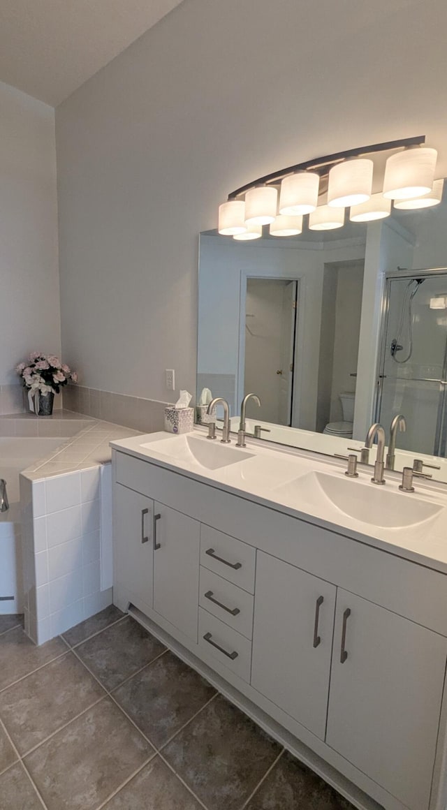 bathroom with double vanity, a stall shower, toilet, and a sink