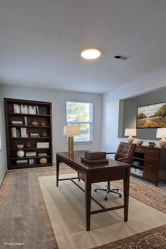 office space featuring visible vents, light colored carpet, and a textured ceiling