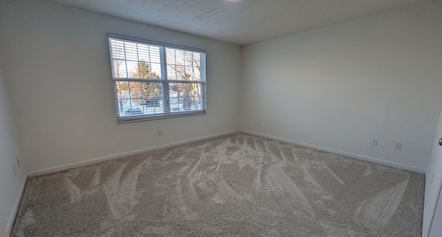 unfurnished room with baseboards, carpet floors, and a textured ceiling