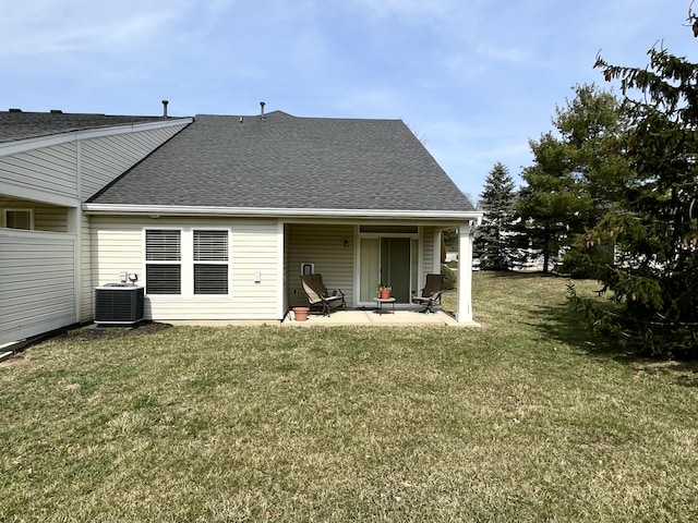 rear view of house with a yard, cooling unit, a patio, and roof with shingles