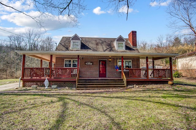 farmhouse-style home with a chimney, brick siding, covered porch, and a front yard