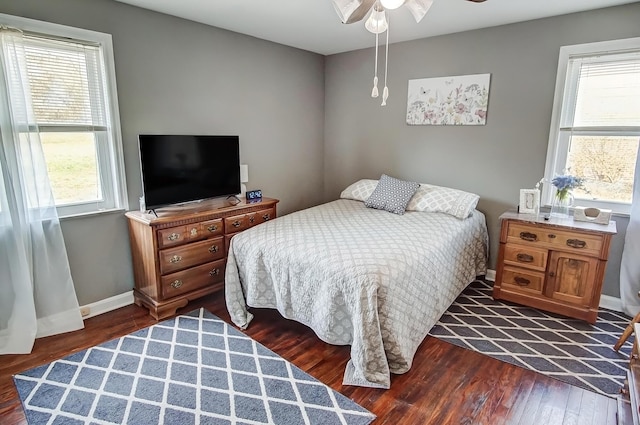 bedroom with multiple windows, dark wood-style floors, and baseboards