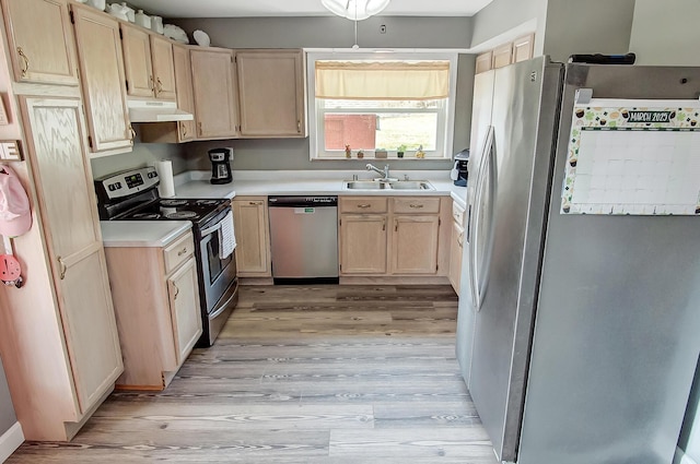 kitchen featuring under cabinet range hood, light brown cabinets, appliances with stainless steel finishes, and a sink