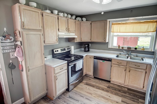 kitchen featuring light brown cabinets, under cabinet range hood, a sink, appliances with stainless steel finishes, and light countertops