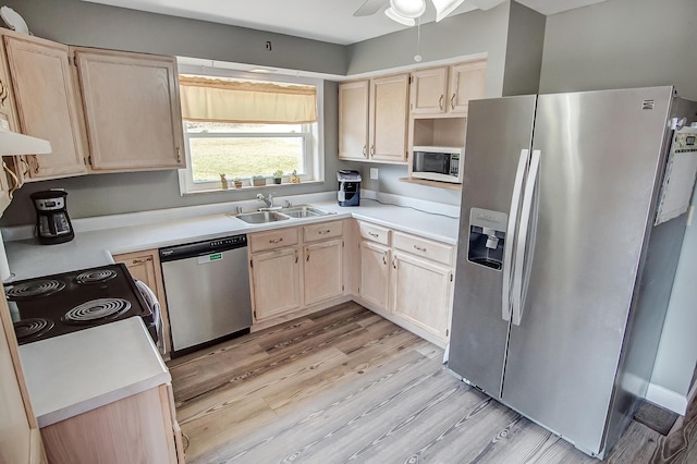 kitchen featuring light brown cabinetry, a sink, stainless steel appliances, light wood-style floors, and light countertops