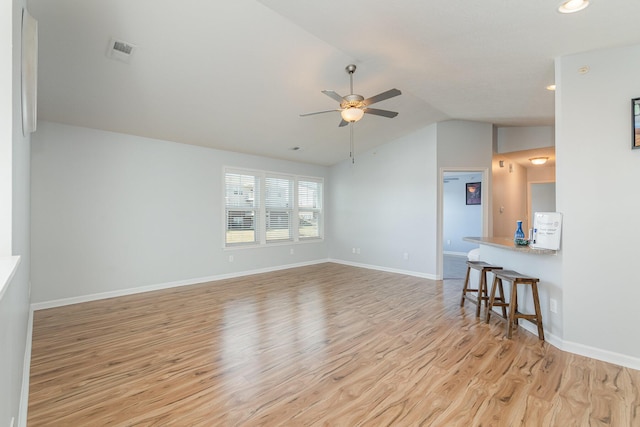 unfurnished living room featuring light wood-type flooring, visible vents, baseboards, ceiling fan, and vaulted ceiling