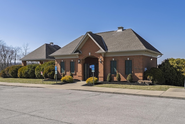 view of front of home featuring brick siding, a chimney, and roof with shingles