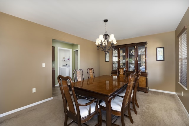 carpeted dining room with an inviting chandelier, washing machine and dryer, and baseboards