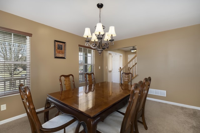 dining space with visible vents, a notable chandelier, carpet, and baseboards