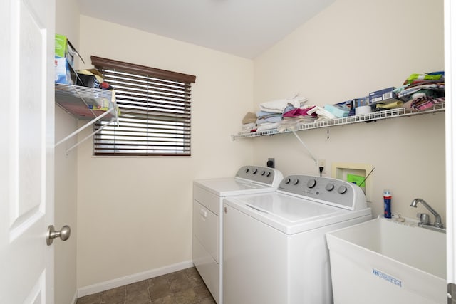 washroom with a sink, baseboards, laundry area, and washer and clothes dryer