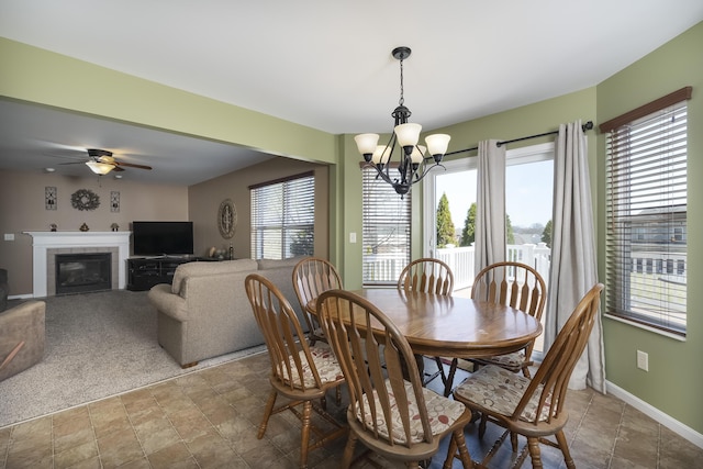 dining area featuring ceiling fan with notable chandelier, a tile fireplace, and baseboards