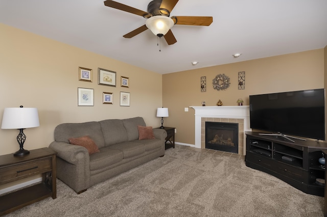 living room with a tiled fireplace, carpet flooring, a ceiling fan, and baseboards