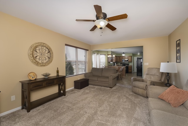 living room with baseboards, light colored carpet, and a ceiling fan