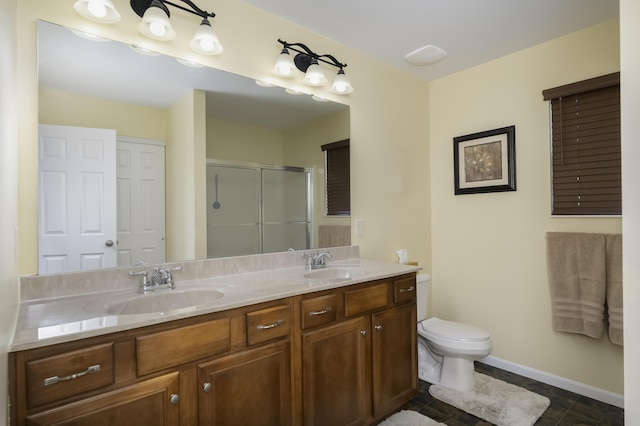 full bath featuring double vanity, a shower stall, toilet, and a sink