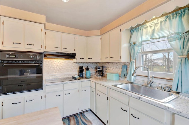 kitchen with a sink, backsplash, under cabinet range hood, and light countertops