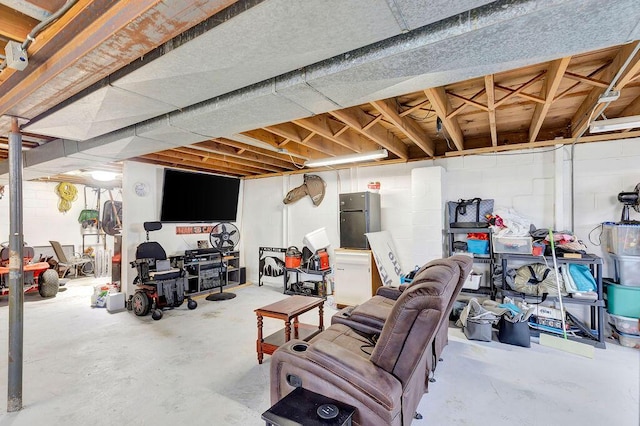 unfinished below grade area with concrete block wall and freestanding refrigerator