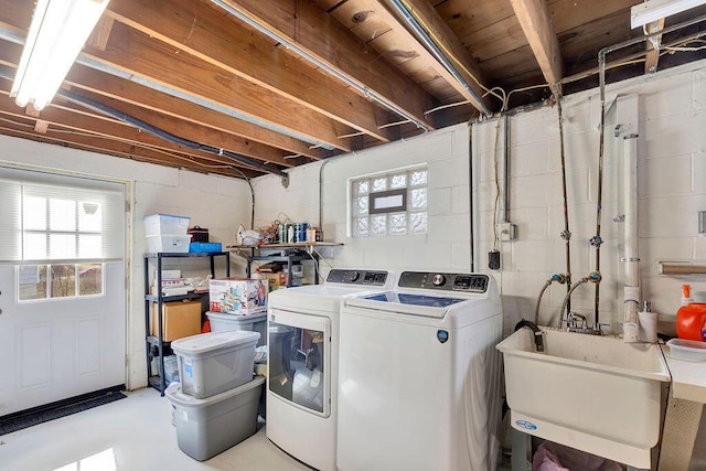 washroom with a sink, concrete block wall, independent washer and dryer, and laundry area