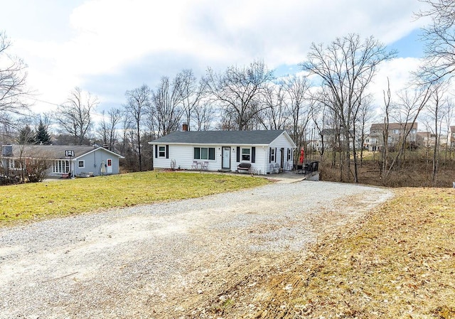 ranch-style home with driveway, a chimney, and a front lawn