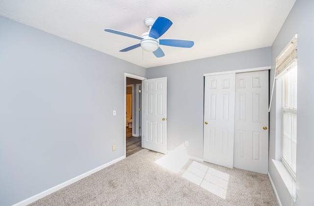 unfurnished bedroom featuring a textured ceiling, a closet, carpet floors, baseboards, and ceiling fan