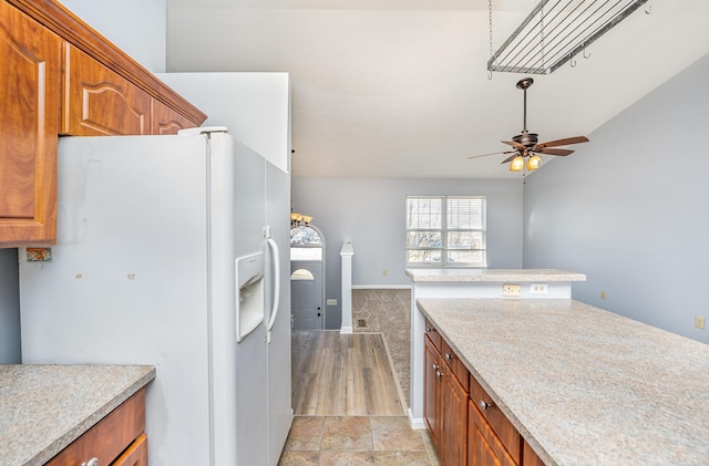 kitchen featuring brown cabinets, light countertops, ceiling fan, and white fridge with ice dispenser