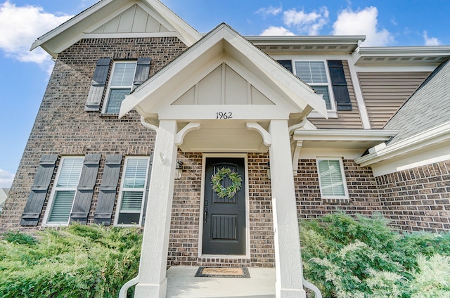 doorway to property featuring brick siding and board and batten siding