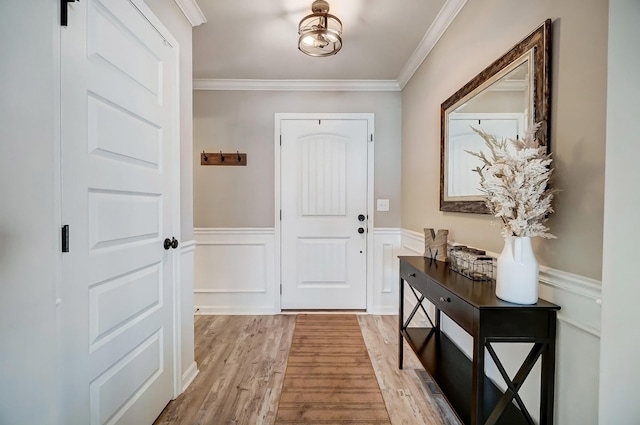 foyer featuring light wood-style floors, a wainscoted wall, and ornamental molding