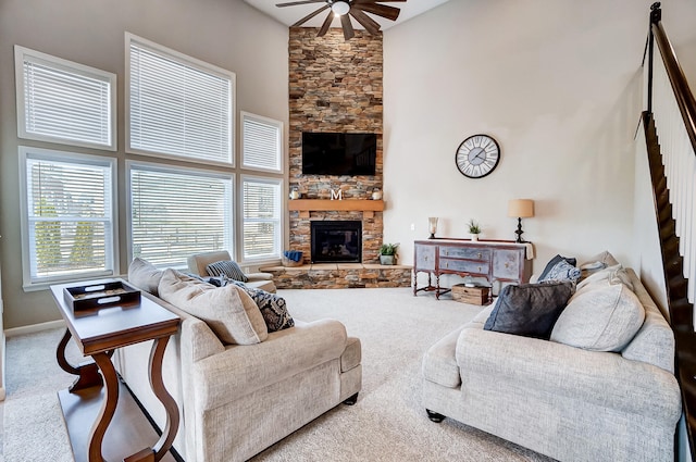 living room featuring a stone fireplace, carpet, a high ceiling, and a ceiling fan