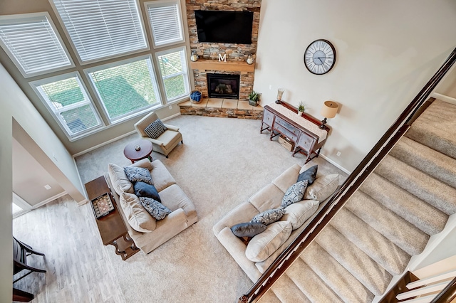 living area featuring a stone fireplace, carpet flooring, and baseboards