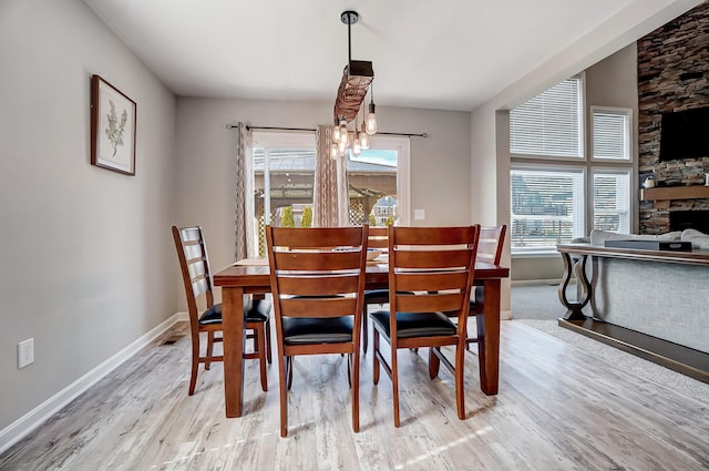 dining area featuring a fireplace, wood finished floors, baseboards, and a chandelier